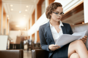 portrait-of-businesswoman-reading-document-female-professional-in-hotel-lobby-examinin-SBI-301326769